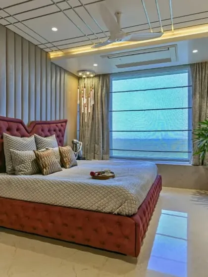 This bedroom features a dramatic winged headboard in a rich burgundy velvet. The design is complemented by a geometrically patterned ceiling and a sleek, modern dresser, creating a look of pure luxury.