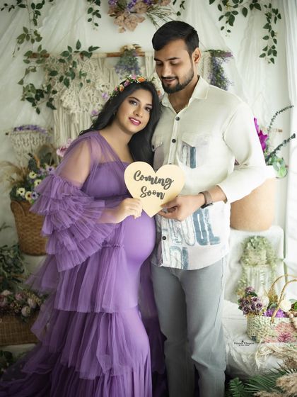 A cute announcement photo from a couple's maternity session. They hold a "Coming Soon" sign, sharing their happy news in a beautifully styled setting.