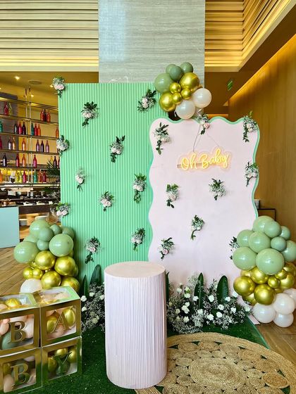 A pastel-themed baby shower with a modern, wavy backdrop in pink and green. We added gold 'BABY' blocks and soft floral accents for a chic and playful look.