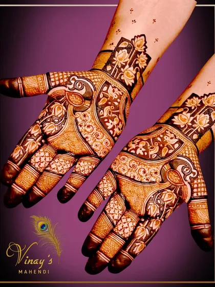 A gorgeous design with a peacock as the main element, surrounded by floral vines that extend up the fingers.