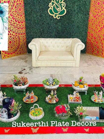 A beautiful engagement setup with a Ganesha-themed backdrop. The platter arrangement includes photo cutouts of the couple, adding a lovely personal touch.