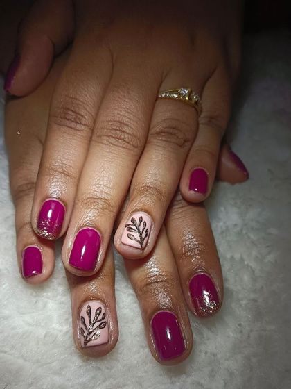 My experts can make your natural nails look this gorgeous. This set has a rich magenta polish with a nude accent nail, glitter, and a hand-painted leaf design.