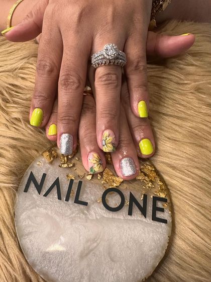 This angle showcases the contrast between the glossy yellow polish and the textured silver glitter nail. We love mixing finishes to create a dynamic and eye-catching look.