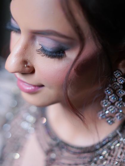A close-up on the bride's glamorous makeup for her cocktail party, highlighting the smoky eyes and elegant earrings.
