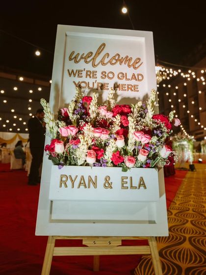 A warm and personal welcome for guests. This custom welcome sign, adorned with a beautiful floral arrangement, sets a gracious and inviting tone for the reception.