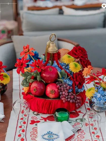 A vibrant table centrepiece featuring fresh pomegranates and colourful flowers at a wedding in Turkey. We use local produce to create decor that is both beautiful and thematic.