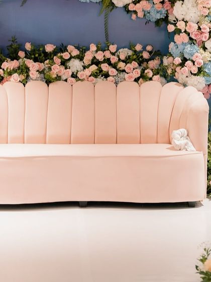 A close-up of the shell-shaped pink velvet sofa, set against the dreamy pastel floral backdrop. Every element was chosen to contribute to the soft, romantic, and minimal aesthetic of the event.