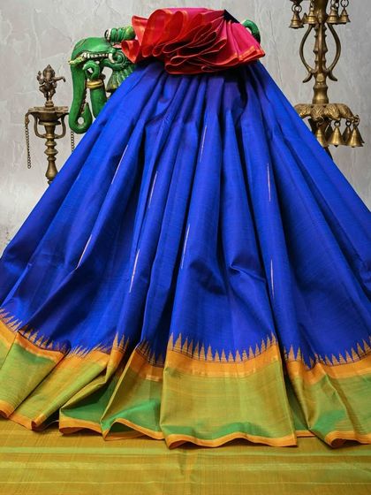 A magnificent royal blue Kanjivaram silk saree with a unique temple border in green and gold. The striking color combination and pure zari work make this a standout piece for any grand event.