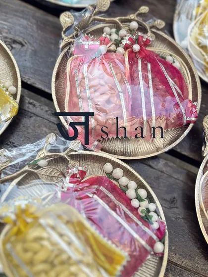 The "Jashn" collection, a celebration of warmth and elegance. These utilitarian decor platters hold organza potlis filled with roasted nuts, showcasing a blend of traditional aesthetics and modern gifting.