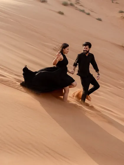 Running hand-in-hand through the golden dunes of Dubai. This dynamic shot captures the couple's adventurous spirit and the stunning, sweeping landscape of the desert.