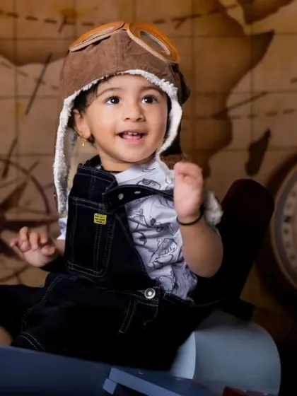 A happy co-pilot ready for adventure. The vintage airplane and world map backdrop set the stage for a journey of imagination.
