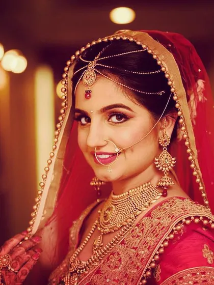 A classic bridal portrait where the focus is entirely on the bride. Using a 70-200mm lens, I created a soft, out-of-focus background that makes her expression and the intricate details of her red lehenga and jewelry stand out.