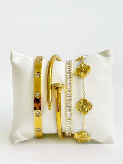 A creative display of gold bracelets on a white cushion. This unique presentation is more engaging than a standard flatlay and works well for social media or website hero images.