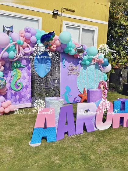 Another view of the outdoor mermaid-themed stage. This shot highlights the shimmering sequin and scale-patterned backdrops, along with the custom marquee letters and balloon garlands.