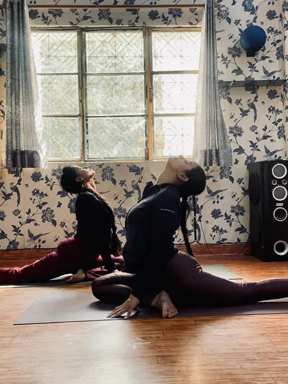Two students practicing Hanumanasana (Monkey Pose or splits) in sync. This advanced pose requires significant hip and hamstring flexibility, built over time with dedicated practice.