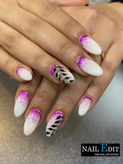 A chic design combining a white base with purple glitter accents at the cuticle. The look is completed with an accent nail featuring a hand-painted black and white leaf design.