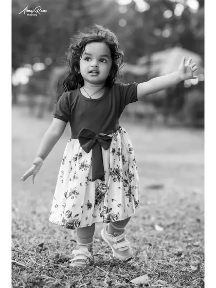 The black and white version of Riona walking in the park. The focus is entirely on her movement and expression, creating a timeless portrait of a child at play.