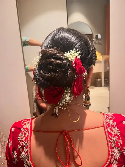 A classic bridal bun with red roses. This timeless hairstyle is perfect for a traditional red lehenga, adding a touch of romance and elegance.