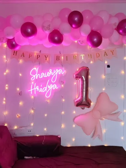 The first birthday home decoration seen with different lighting, showing the vibrant glow of the neon sign.