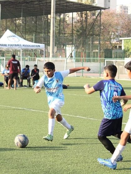 An action shot from the U12 Blue Cubs League, with the Thane Football Association tents in the background, showing the official nature of these grassroots tournaments.