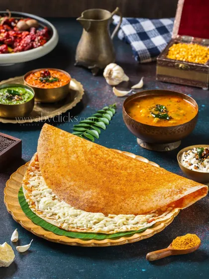 A crispy, golden cheese dosa, shot for a restaurant menu. The lighting is focused on making the cheese look melted and delicious, with traditional accompaniments in the background.