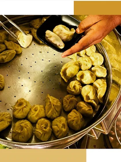 A chef serving freshly steamed momos from a large steamer, ensuring every guest gets a hot and delicious bite.