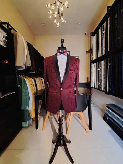 A custom maroon tuxedo with a subtle geometric pattern and a classic black shawl lapel. Displayed in my studio, this piece is ready for a festive occasion like a Christmas party or a wedding reception.