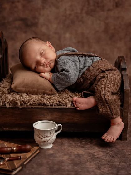 Dreaming of cookies. This adorable setup features a newborn sleeping on a miniature bed with a jar of cookies nearby, creating a sweet and whimsical scene.