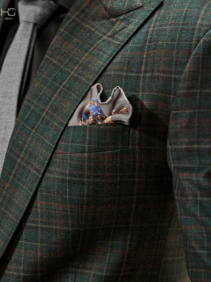 A close-up on the details of the green checked suit. The texture of the fabric, the subtle pattern, and the perfectly chosen pocket square all contribute to its refined character.