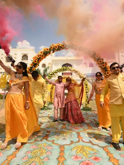 A fun Haldi entry with the couple and their family walking under an arch of hands and colorful smoke.
