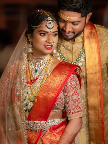 A beautiful couple portrait. The bride's red blouse, fully embroidered with beadwork, perfectly complements her red and gold wedding saree.