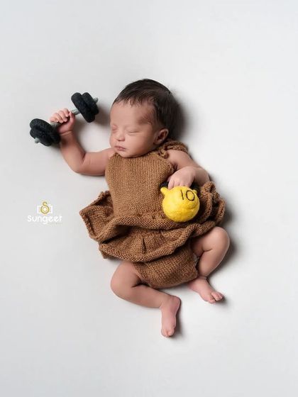 Starting them young! This humorous setup shows a newborn "lifting" a tiny dumbbell. It's a playful and unique concept that always brings a smile to parents' faces.