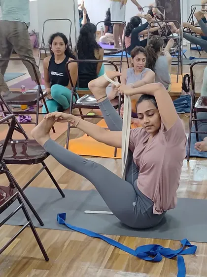 Using a strap to assist in this complex seated hip-opening pose. The strap acts as an extension of the arms, allowing the student to work on the posture with better alignment.
