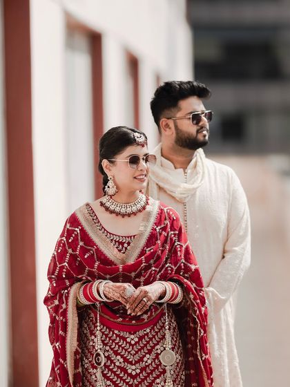A stylish portrait of the couple posing with sunglasses. Their confident stance and coordinated outfits make for a cool and modern image.