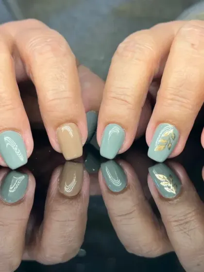 A calming and earthy manicure with a mix of sage green and beige nails, accented with delicate gold leaf art.