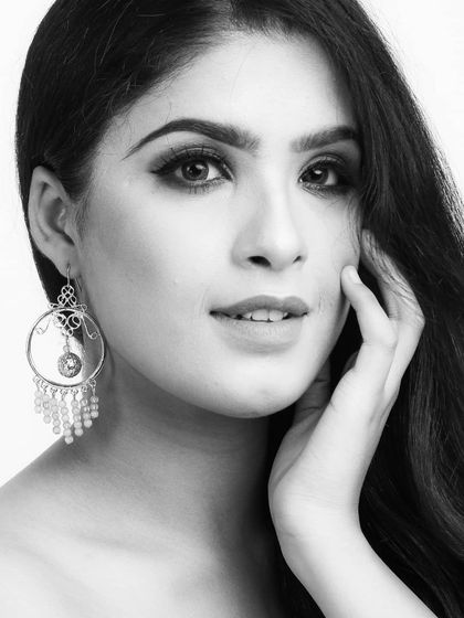 A black and white beauty shot of a model, with the focus on her expressive look and a large, ornate earring.