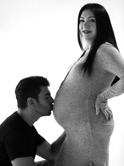 A full-length view of a sweet moment between expecting parents. This classic pose highlights the baby bump and the supportive embrace of the partner.