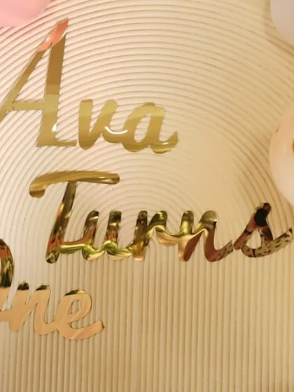 A close-up of the custom gold acrylic lettering for "Ava Turns One," adding a touch of luxury and personalization to the backdrop.