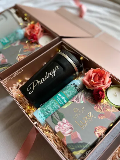 Inside the personalized bridesmaid box, you'll find a custom-engraved tumbler, luxury chocolates, and other treats, all nestled in festive filling.