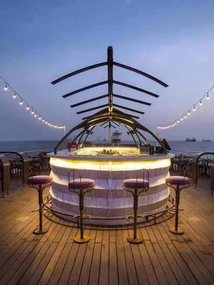 A frontal view of the custom-designed bar on the Queensline Sea Yah. The design features a translucent, illuminated base and a distinctive skeletal canopy, making it a functional sculpture and a focal point of the deck.