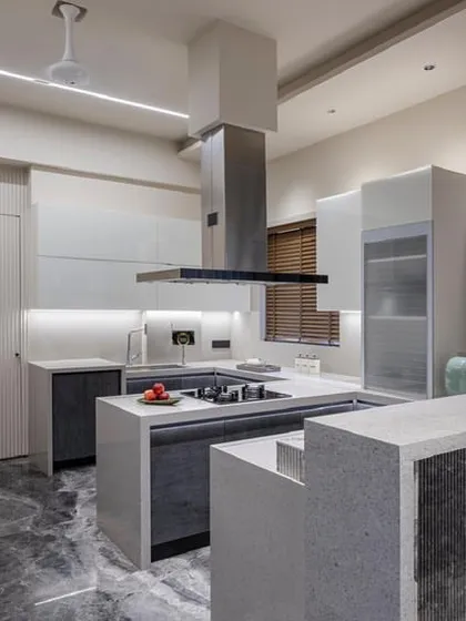 The multi-level island serves as both a prep area and a breakfast bar. The use of marble with fluted details on the island base adds texture and visual interest.