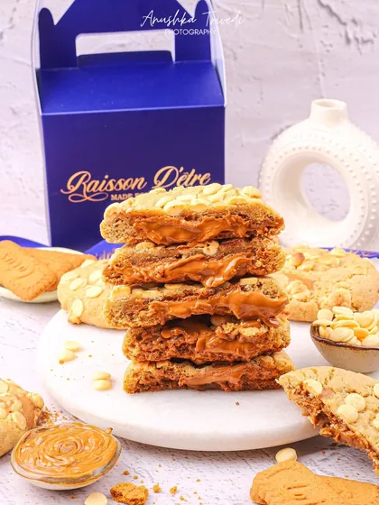 A stack of Biscoff-stuffed cookies, sliced to reveal the creamy center. The composition is designed to look indulgent and irresistible.