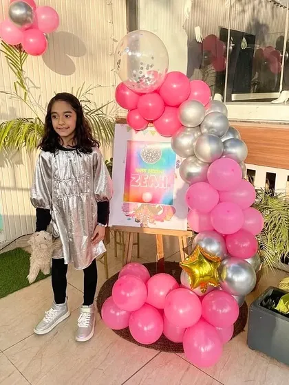 A personalized welcome easel with a pink and silver balloon garland, making the birthday girl feel special from the moment she arrives.