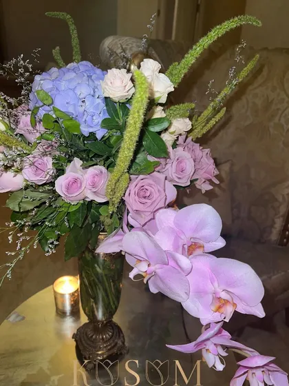 Quiet but opulent. This gorgeous assortment of Phalaenopsis orchids, amaranthus, roses, and hydrangeas creates a sophisticated and luxurious feel. The single candle beside it adds a touch of intimate warmth.