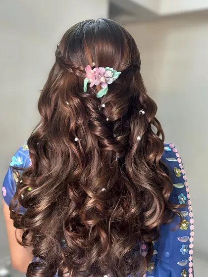 Voluminous curls are always a good idea. This half-up style is adorned with a floral clip and scattered pearls, creating a look that is both glamorous and romantic.