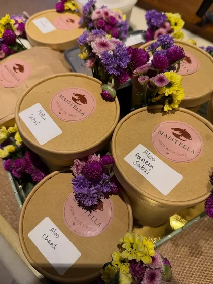 Indian dishes like Aloo Chaat and Aloo Paneer Sabzi packed in our eco-friendly containers, adorned with fresh flowers. Even our deliveries get a special touch.