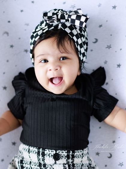 What a happy smile. This little one's joy is infectious. The checkered bow and black-and-white outfit add a touch of modern style to this classic baby portrait.