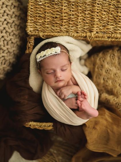 I just can't handle the sweetness! This overhead shot shows the baby perfectly nestled in a basket with soft, neutral-toned fabrics.