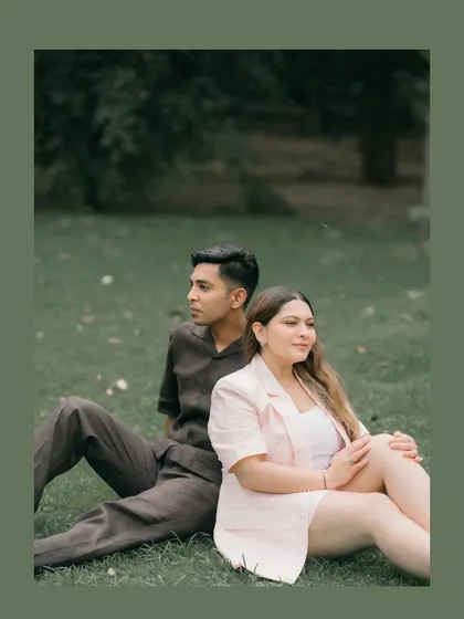 A quiet, contemplative moment for Shubhi and Kunal, sitting back to back in a lush green park. This pose creates a sense of individual strength and shared space, a beautiful metaphor for partnership.