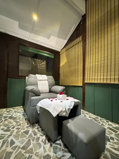 A quiet corner in our Guwahati center, featuring a comfortable pedicure chair set against natural textures like stone flooring and bamboo blinds to create a peaceful, earthy atmosphere.